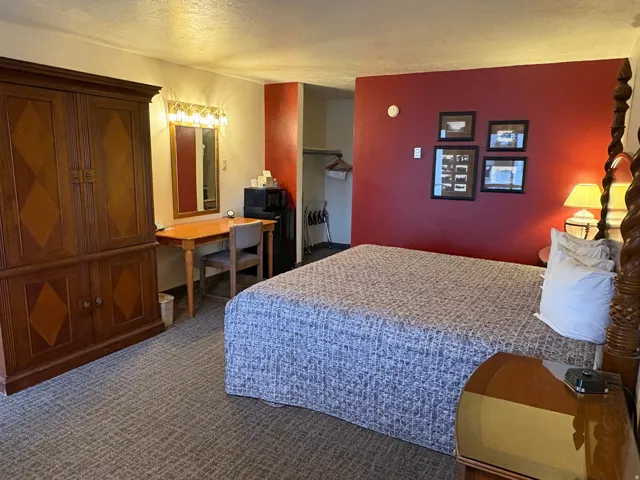 Bedroom featuring an office area, dark colored carpet, and a textured ceiling