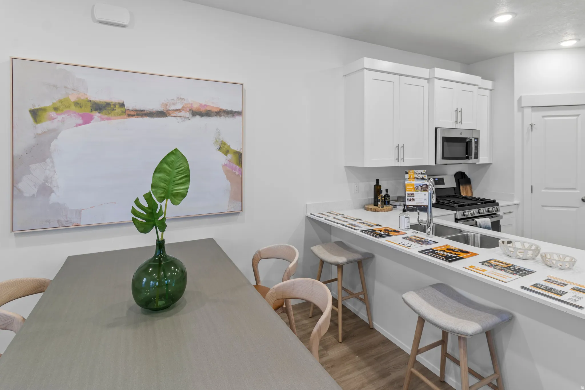 Kitchen featuring a breakfast bar, light countertops, stainless steel appliances, white cabinetry, and light wood finished floors