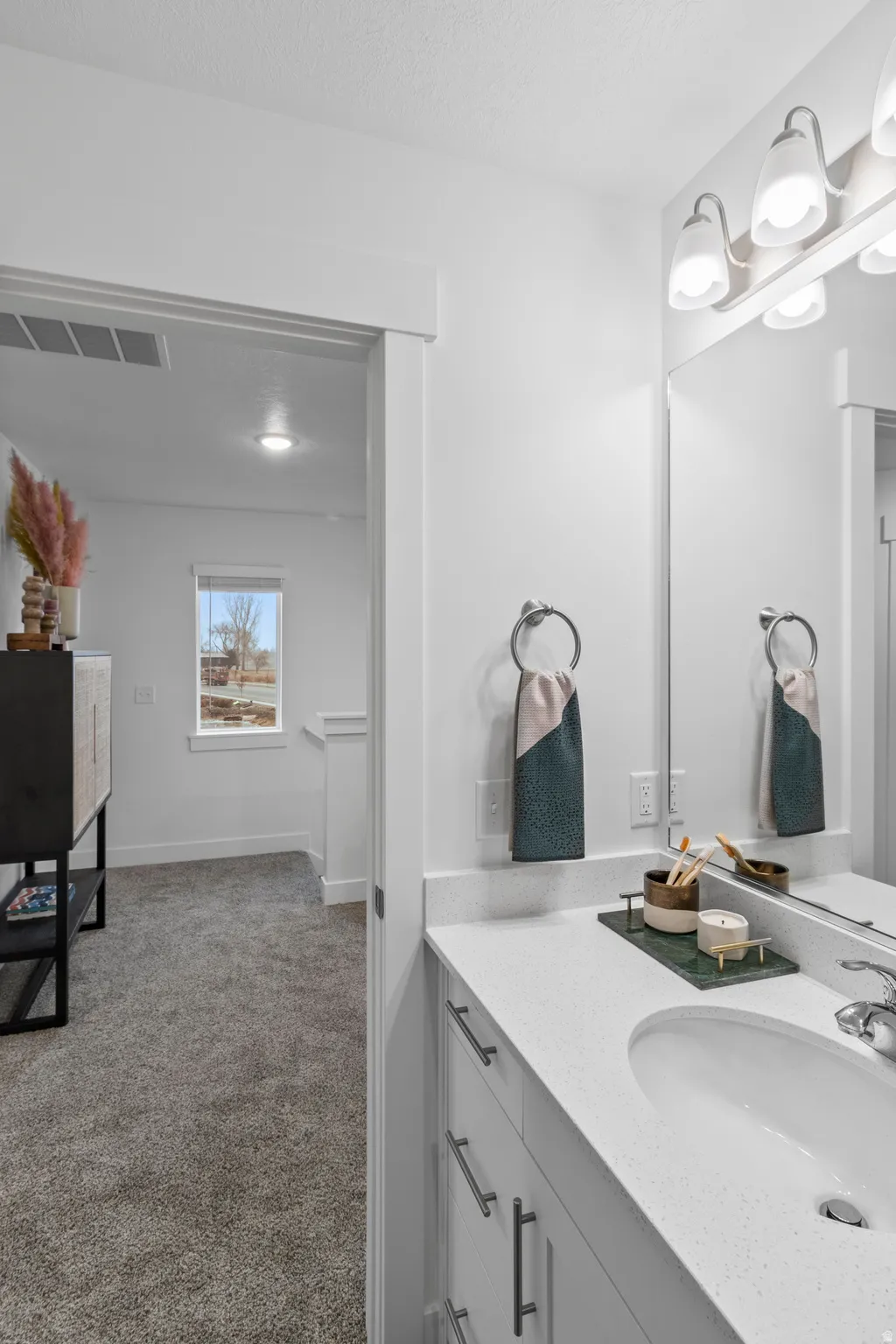 Bathroom with vanity, light carpet, and a textured ceiling