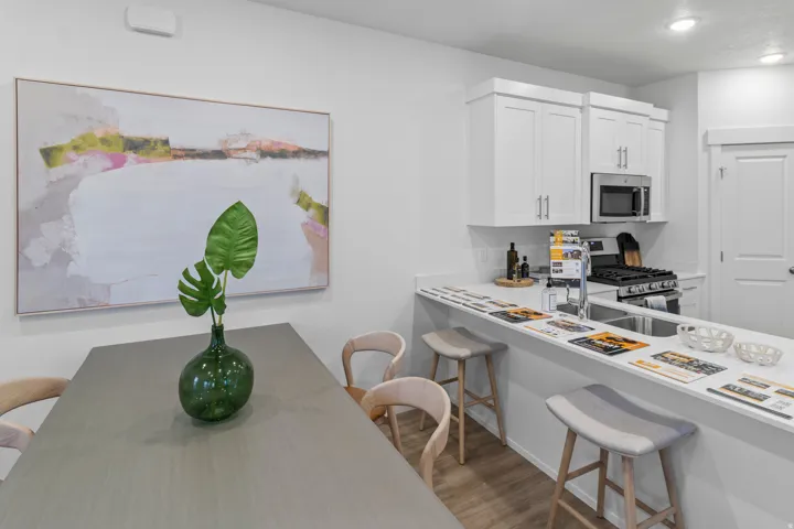 Kitchen featuring a breakfast bar, light countertops, stainless steel appliances, white cabinetry, and light wood finished floors