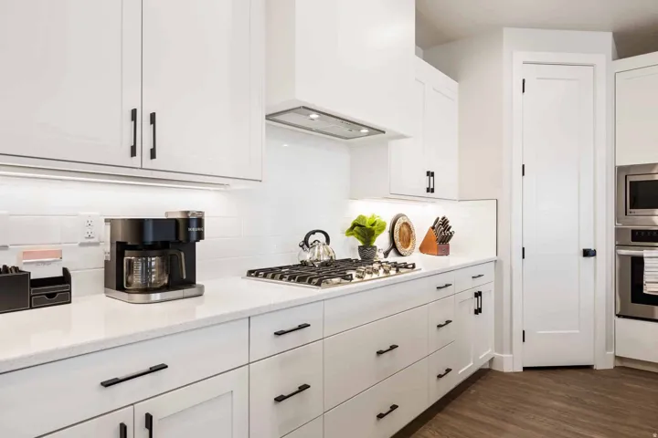 Kitchen featuring white cabinets, stainless steel appliances, dark wood-type flooring, tasteful backsplash, and light stone counters