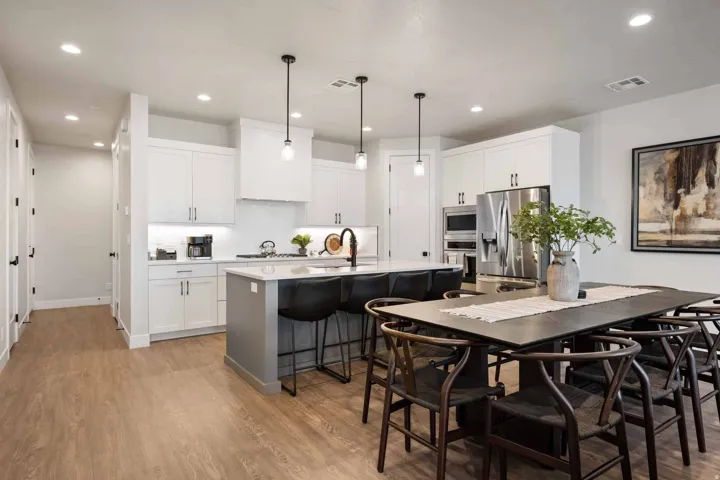 Kitchen with decorative light fixtures, white cabinetry, a kitchen breakfast bar, and light wood-type flooring