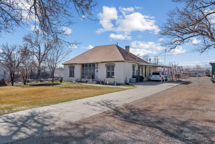 View of front of house featuring concrete driveway, an attached carport, a chimney, a trampoline, and a front lawn