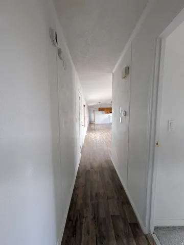 Hallway featuring dark wood-type flooring and crown molding