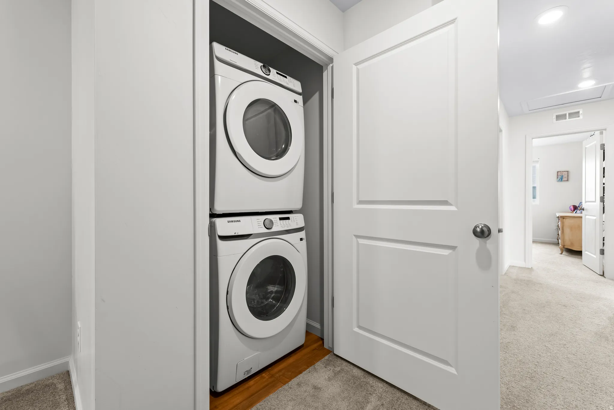 Laundry area with stacked washing machine and dryer, carpet floors, and recessed lighting