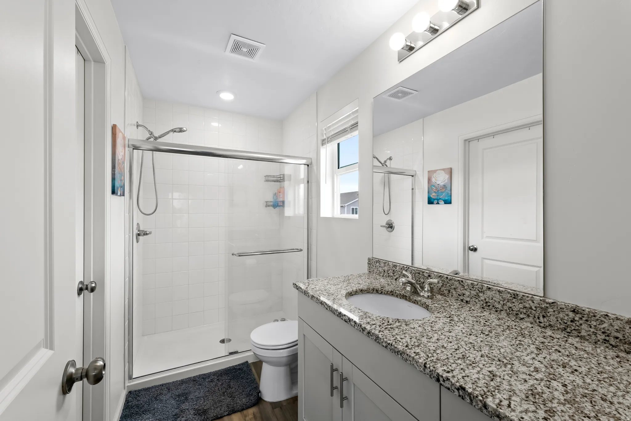 Bathroom with vanity, a shower stall, and dark wood-style floors