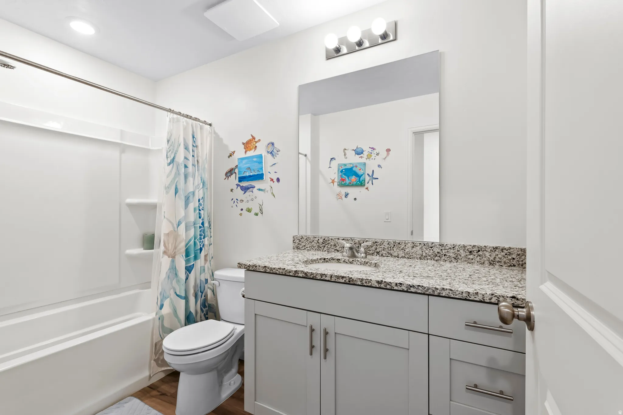 Full bath with shower / tub combo, vanity, and dark wood-style flooring