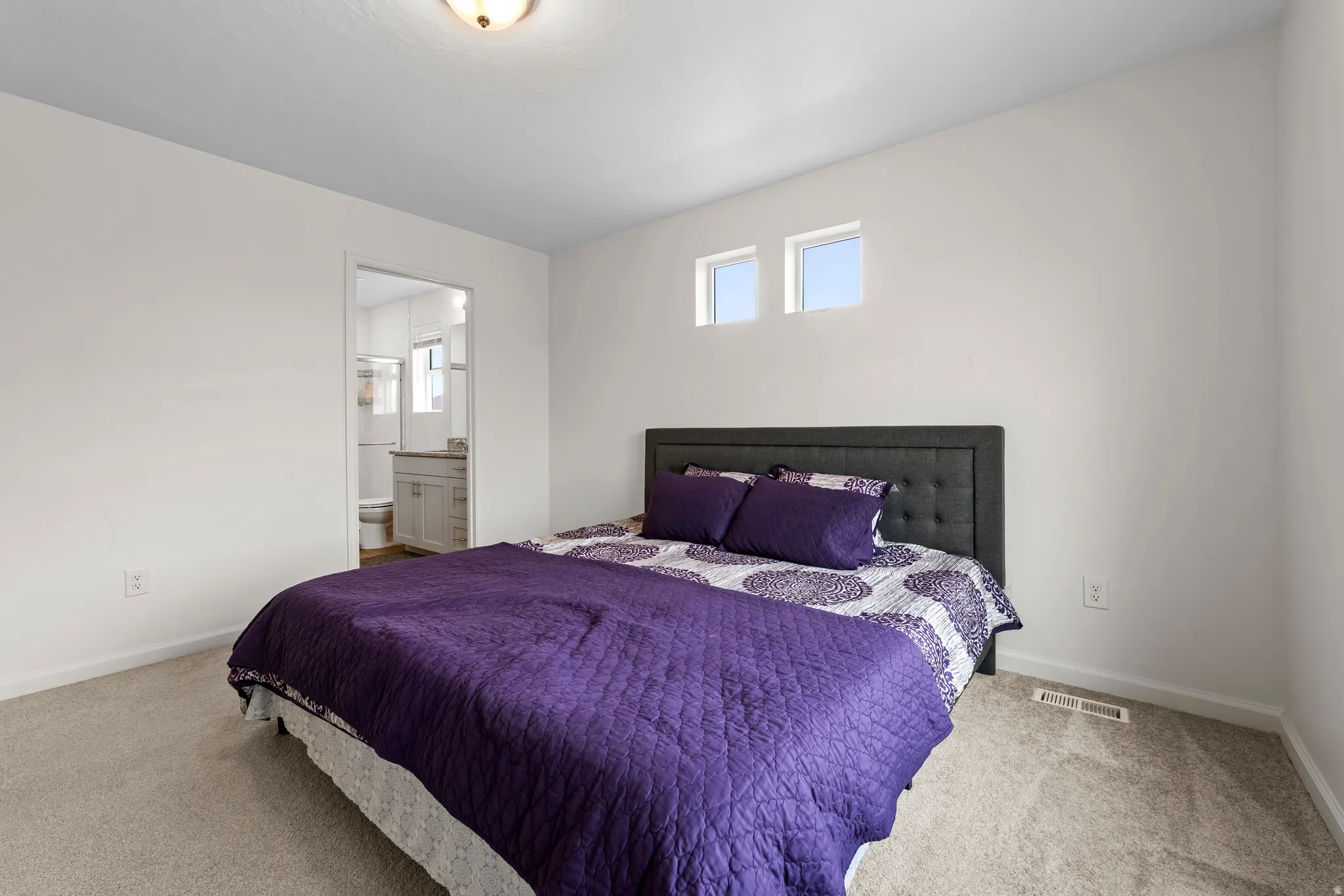 Carpeted bedroom with ensuite bath and baseboards