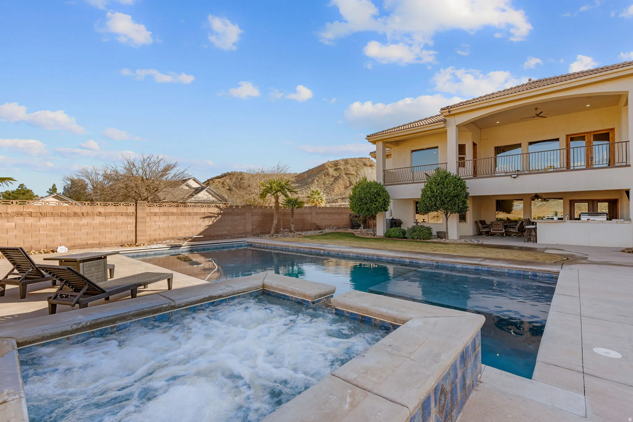 Integrated pool / hot tub with a patio area, a balcony, and a fenced backyard