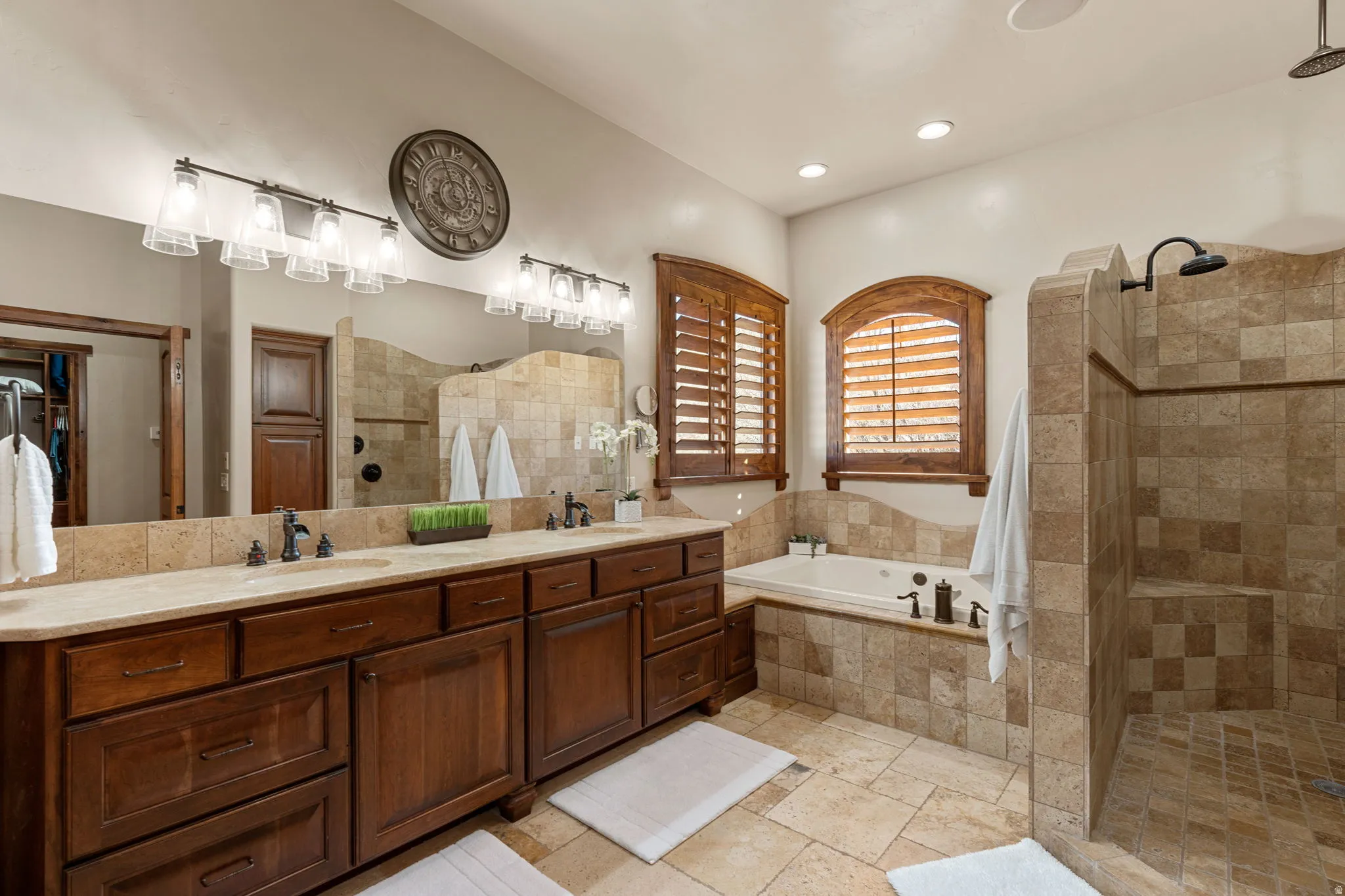 Primary Owner Suite Bathroom with double vanity, a walk in shower, a garden tub, and stone tile flooring