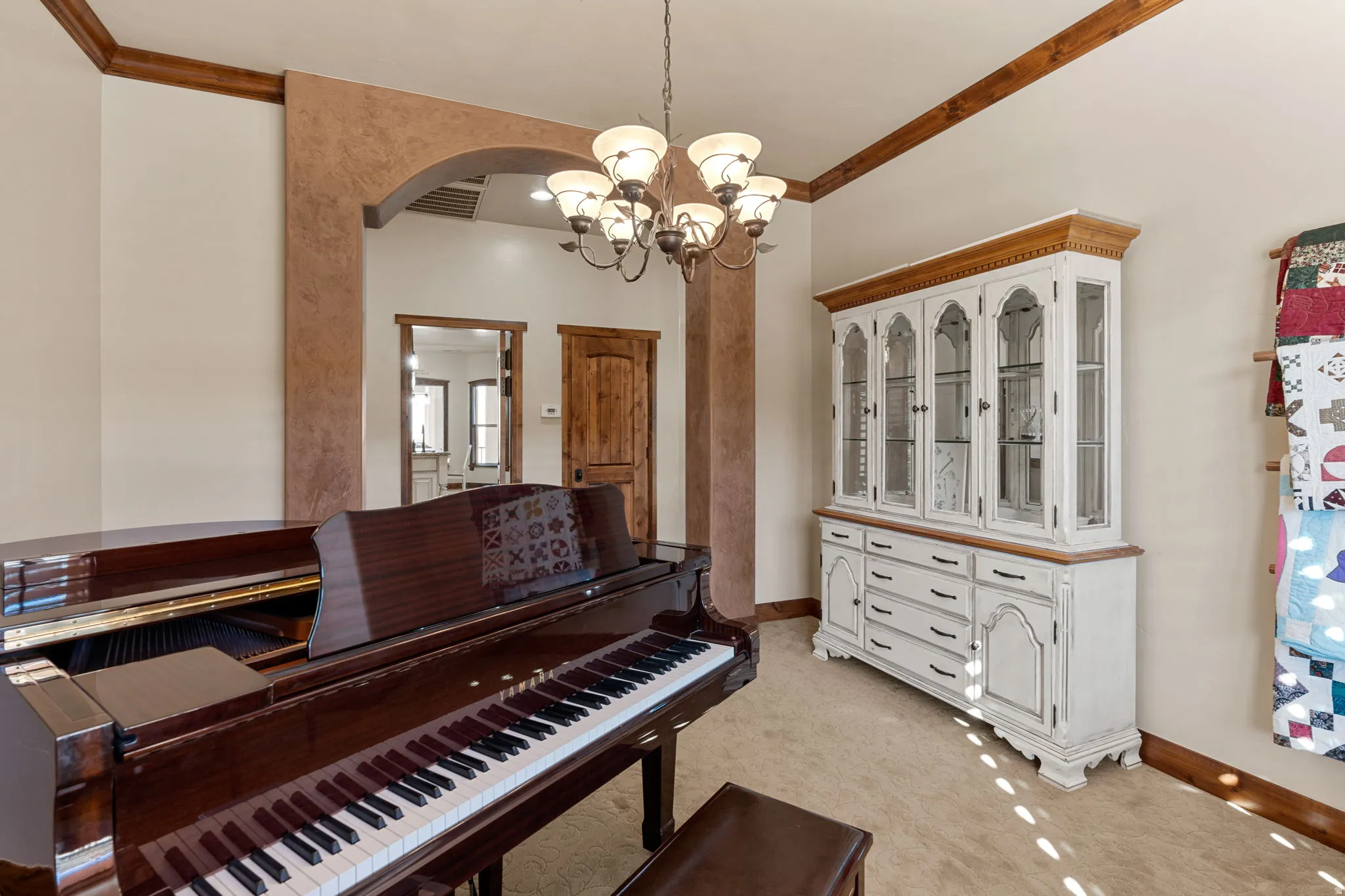Miscellaneous room featuring ornamental molding, a chandelier, arched walkways, and light colored carpet