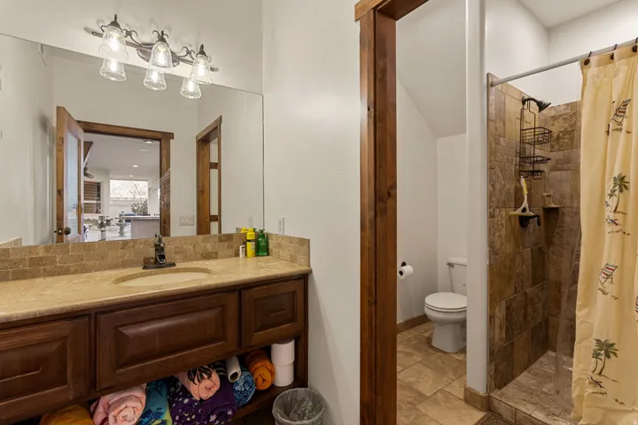 Outside Pool Bathroom featuring a stall shower, vanity, and light stone finish flooring