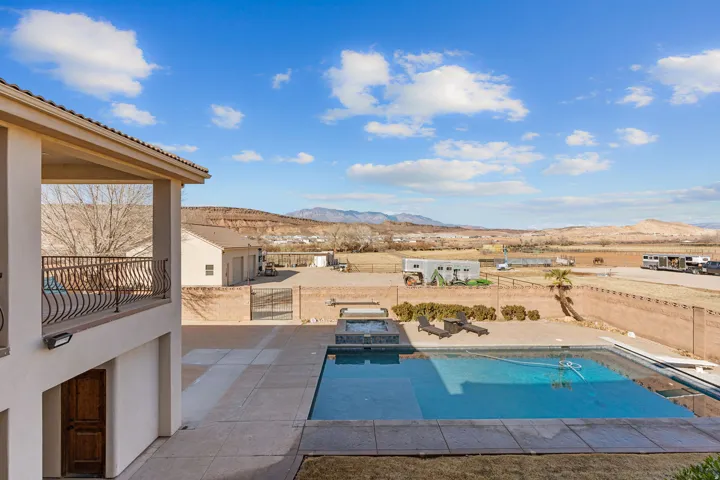 View of swimming pool featuring a mountain view, a jacuzzi, a fenced backyard, patio surround, and a balcony