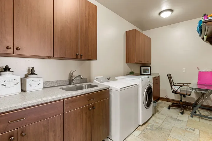 Laundry room featuring stone tile flooring, cabinet space, and washing machine and dryer