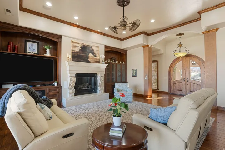 Living area featuring arched walkways, hardwood / wood-style floors, ornamental molding, a premium fireplace, and hanging lights