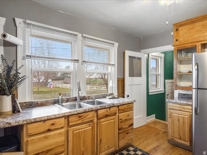 Kitchen with freestanding refrigerator, light wood finished floors, a ceiling fan, and wood finish cabinets