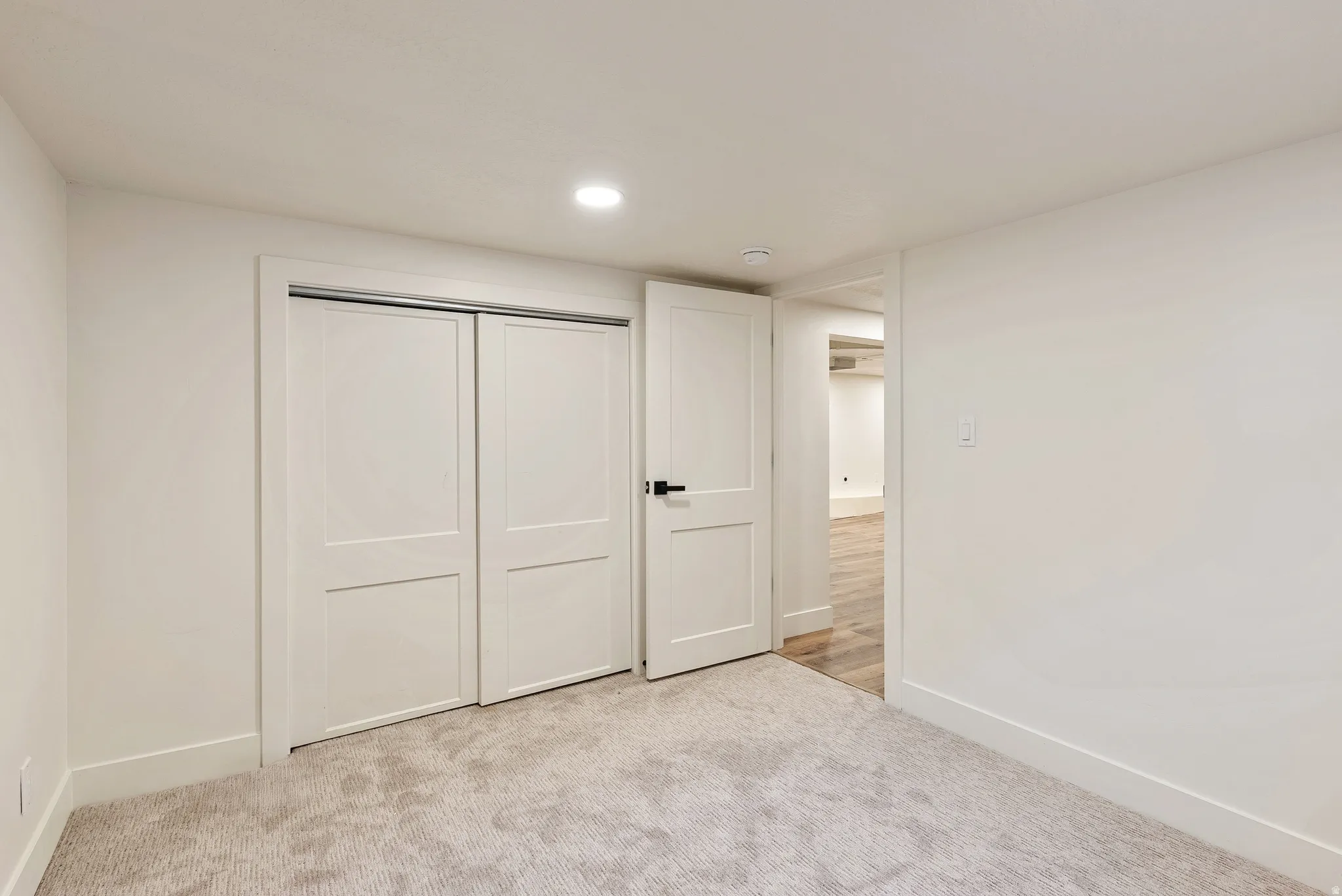 Unfurnished bedroom with a closet, light carpet, and recessed lighting