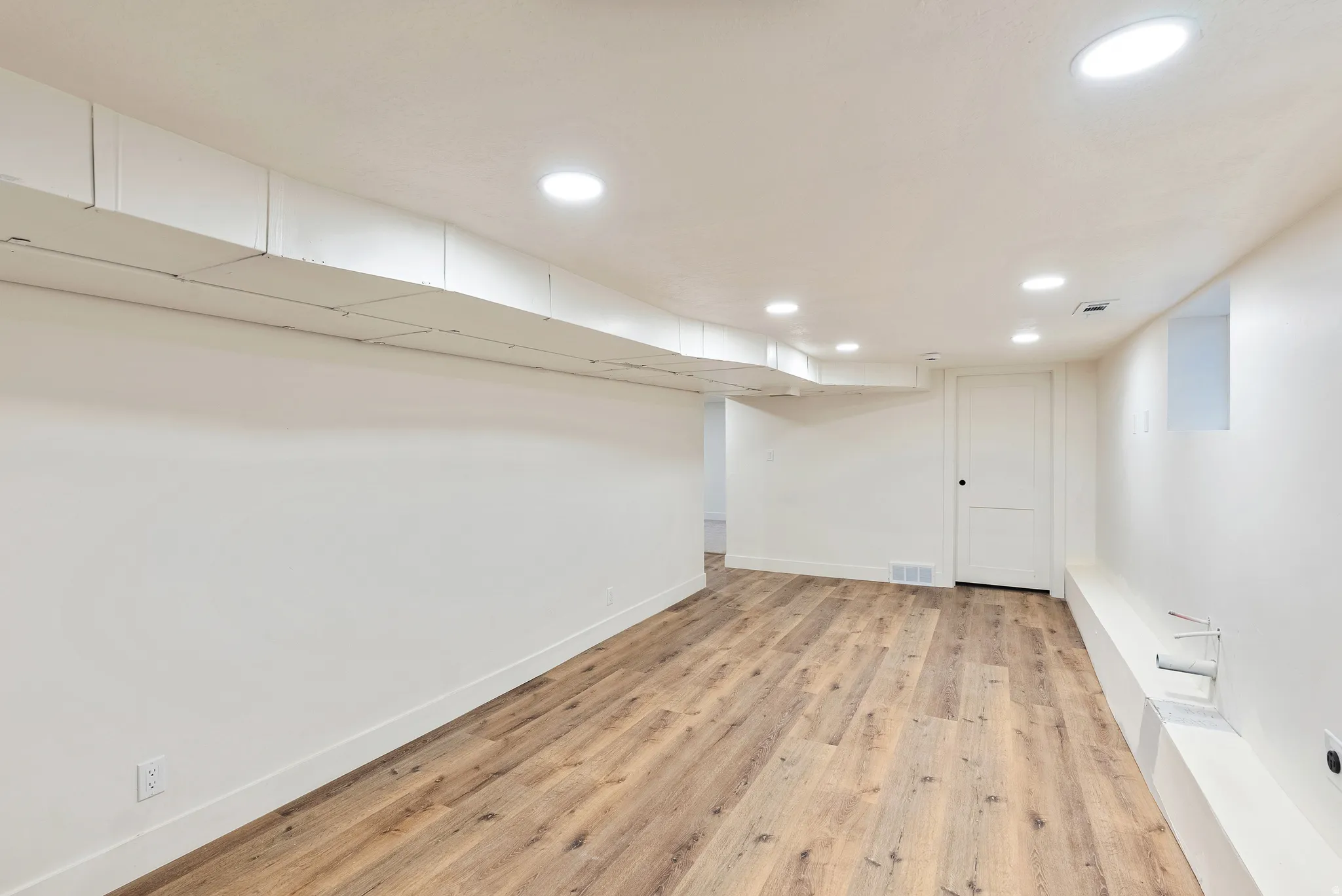Finished basement with light wood-type flooring and recessed lighting