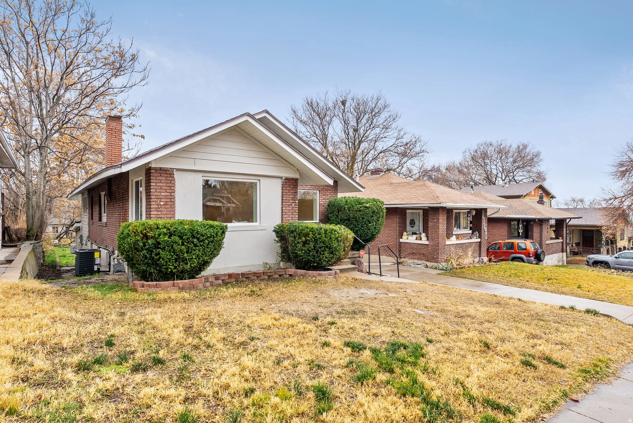 View of front of house featuring brick siding, a chimney, and a front yard