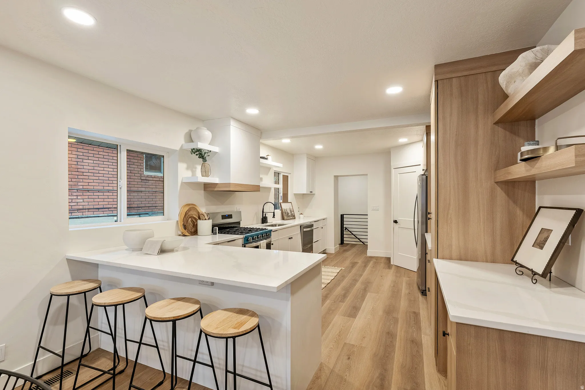 Kitchen with open shelves, a peninsula, a breakfast bar, stainless steel appliances, and recessed lighting