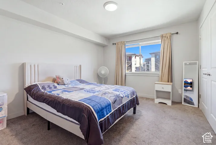 Bedroom featuring neutral wall paint, wall-to-wall carpeting, a horizontal sliding window with decorative drapery hardware, and a closet with dual swing doors