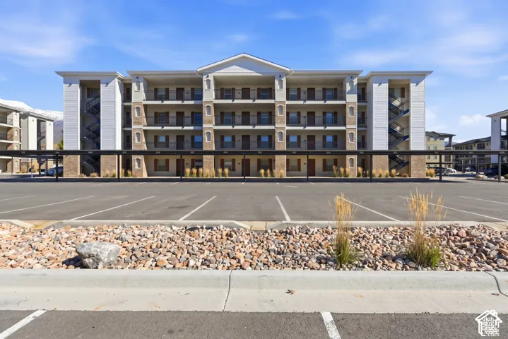 Multi-story exterior featuring stone veneer accents, lap siding, a gabled roofline, private covered balconies, and steel stairwells