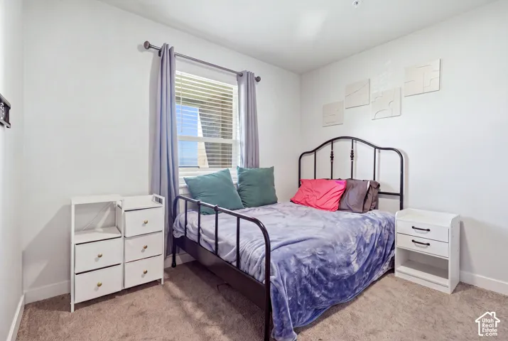 Neutral wall tones, carpeted flooring, and a single-pane window with attached metal curtain rod