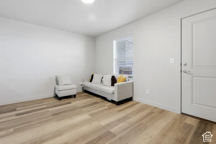 Neutral-toned interior featuring wood-finish flooring, a single-panel interior door with satin nickel hardware, and a window with horizontal blinds
