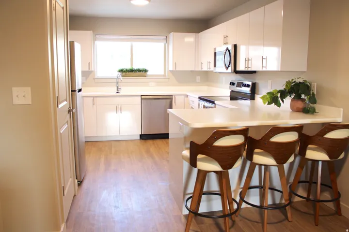 Kitchen with a peninsula, light countertops, a kitchen bar, stainless steel appliances, and white cabinets