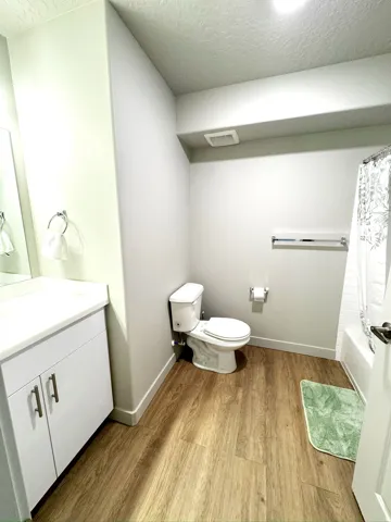 Full bath featuring vanity, a textured ceiling, light wood finished floors, and shower / tub combo with curtain