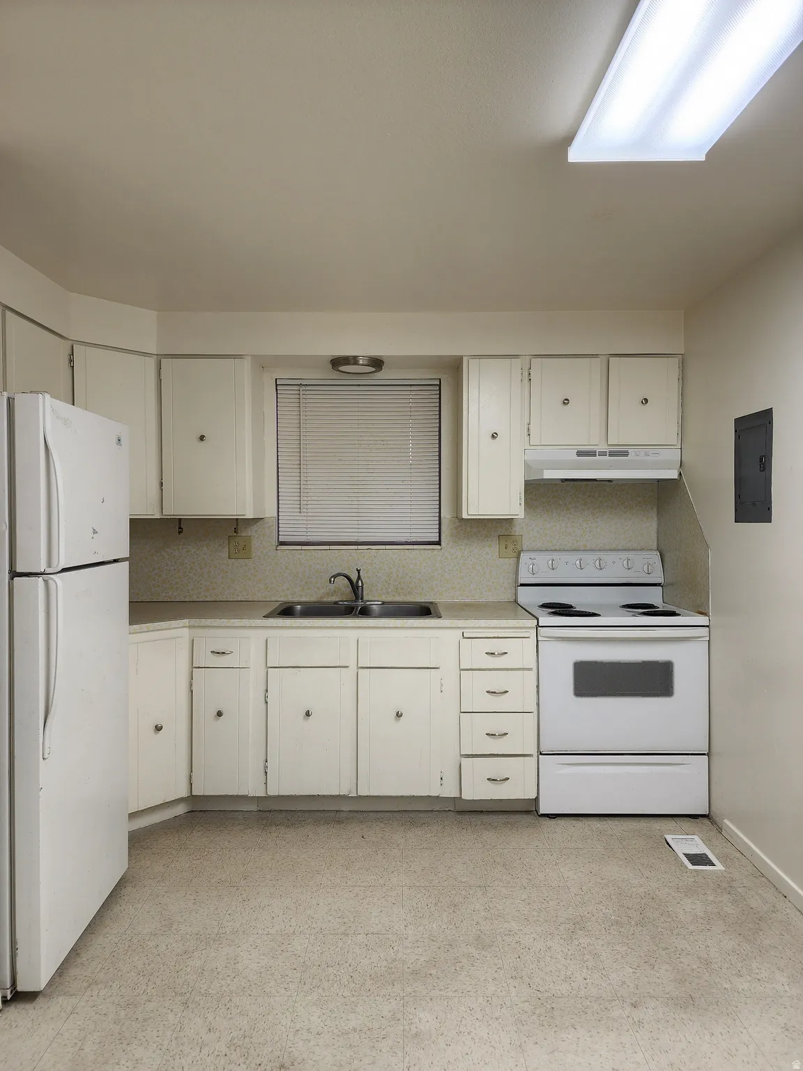 Typical kitchen featuring white cabs and appliances, decorative backsplash with light countertops,