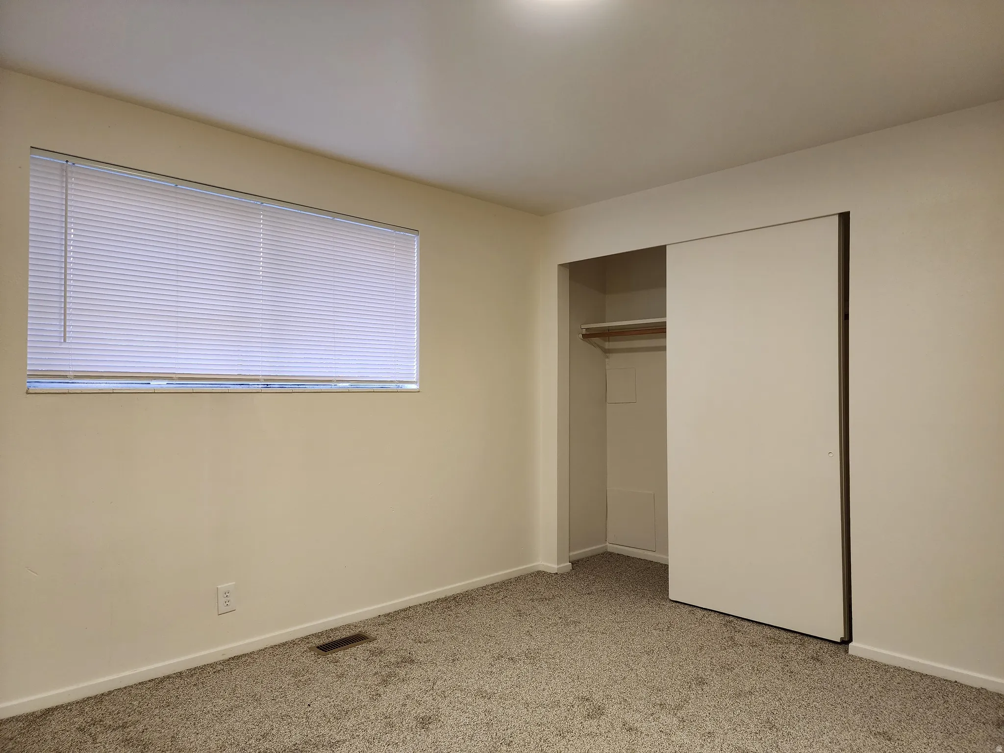 Typical bedroom featuring light colored carpet and good size closet