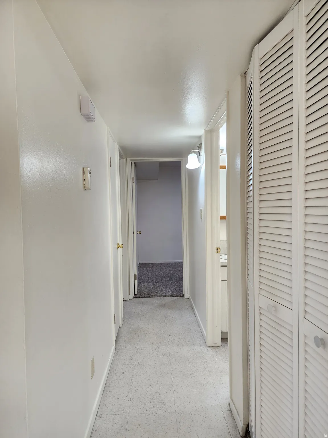 Corridor featuring light flooring and baseboards