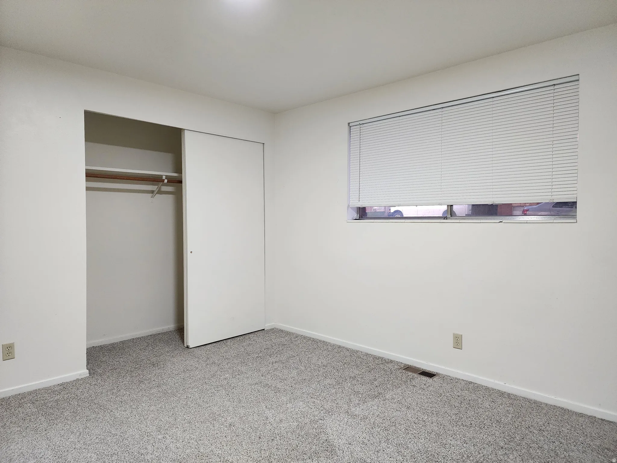 Typical bedroom with light colored carpet and a closet