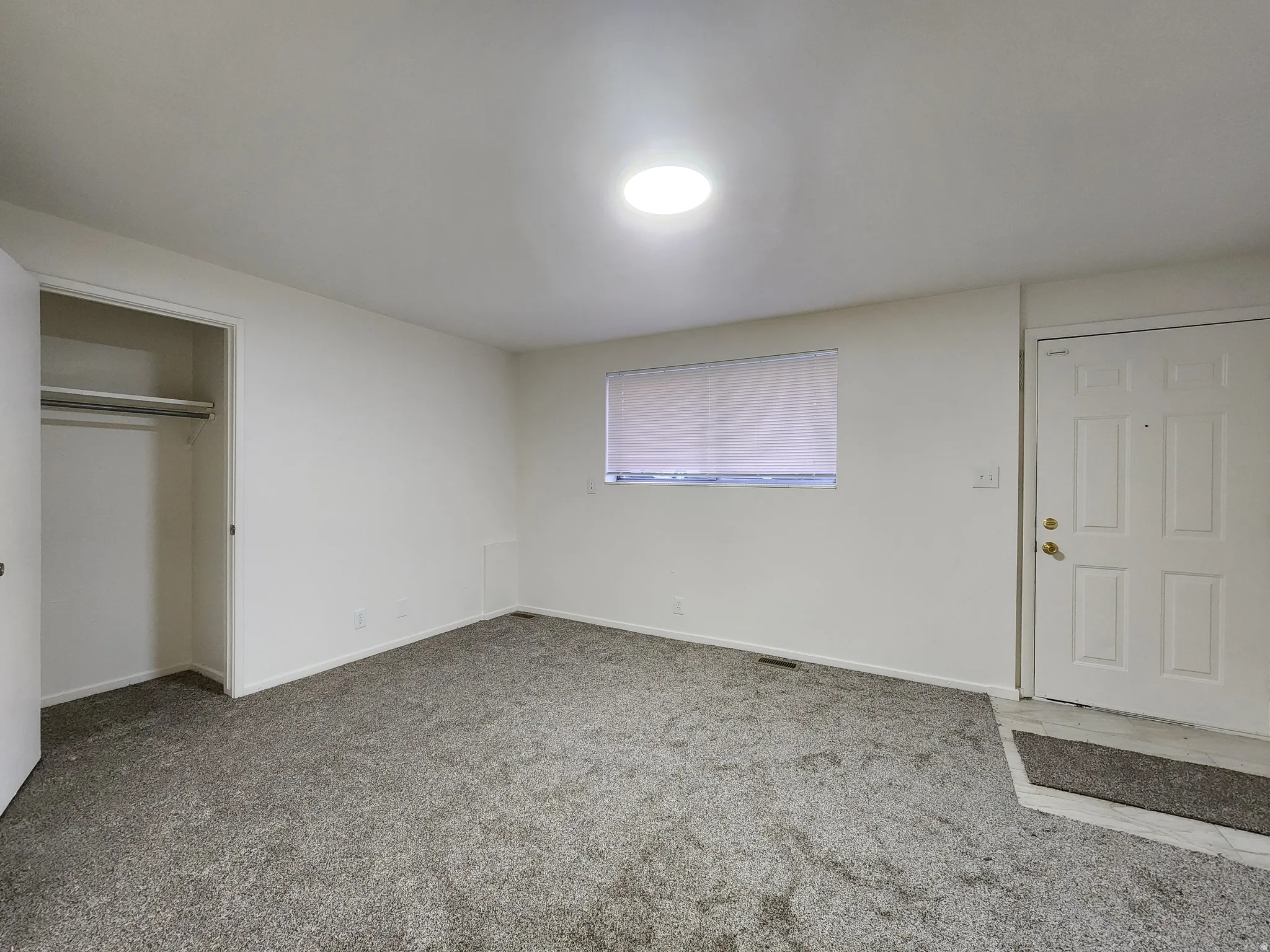 Typical bedroom with light colored carpet and a closet