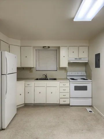 Typical kitchen featuring white cabs and appliances, decorative backsplash with light countertops,