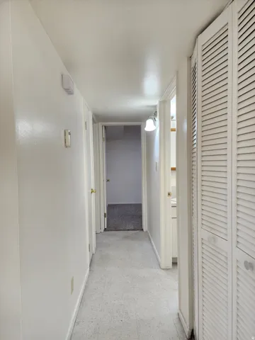 Corridor featuring light flooring and baseboards