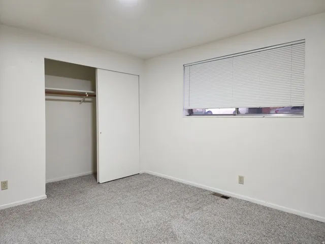 Typical bedroom with light colored carpet and a closet