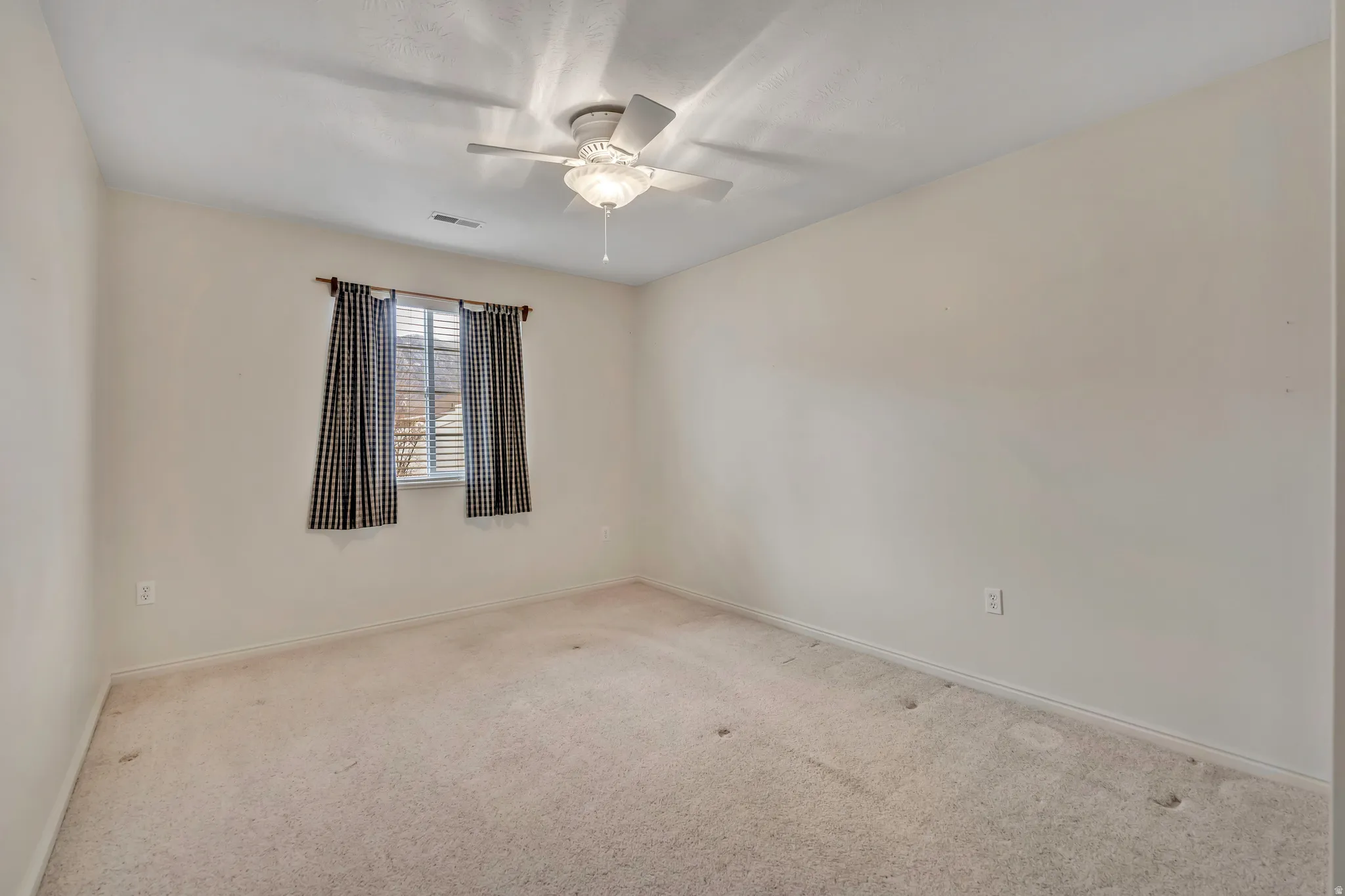 Carpeted spare room with ceiling fan and baseboards