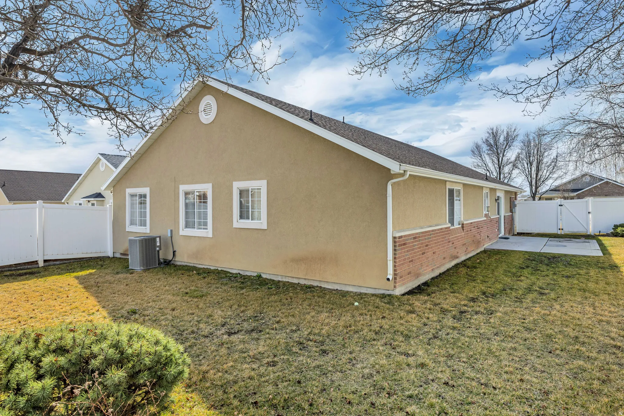 View of property exterior featuring a gate, a fenced backyard, stucco siding, and brick siding