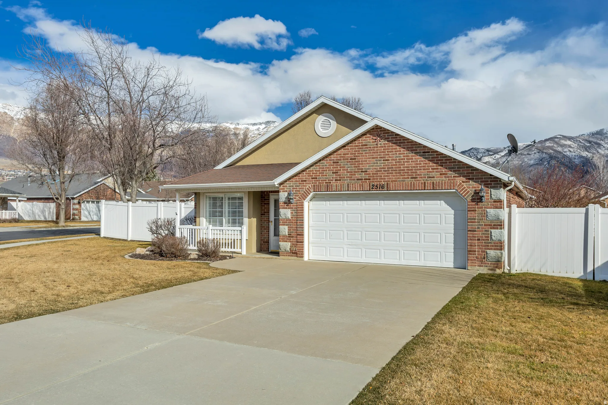 Single story home featuring brick siding, driveway, a garage, covered porch, and a mountain view