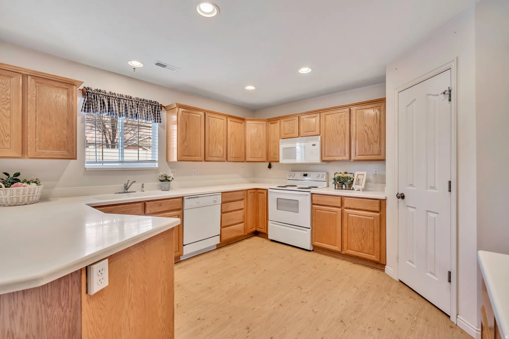 Kitchen with white appliances, light countertops, recessed lighting, light wood finished floors, and light wood finish cabinets