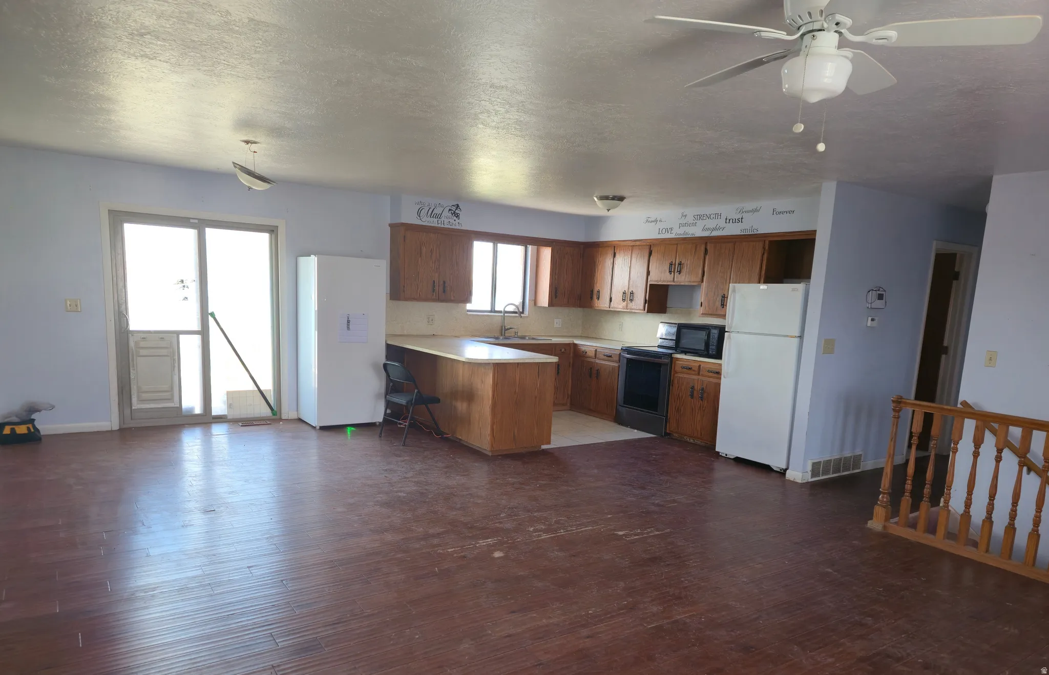 Kitchen featuring light countertops, freestanding refrigerator, a peninsula, a ceiling fan, and a textured ceiling