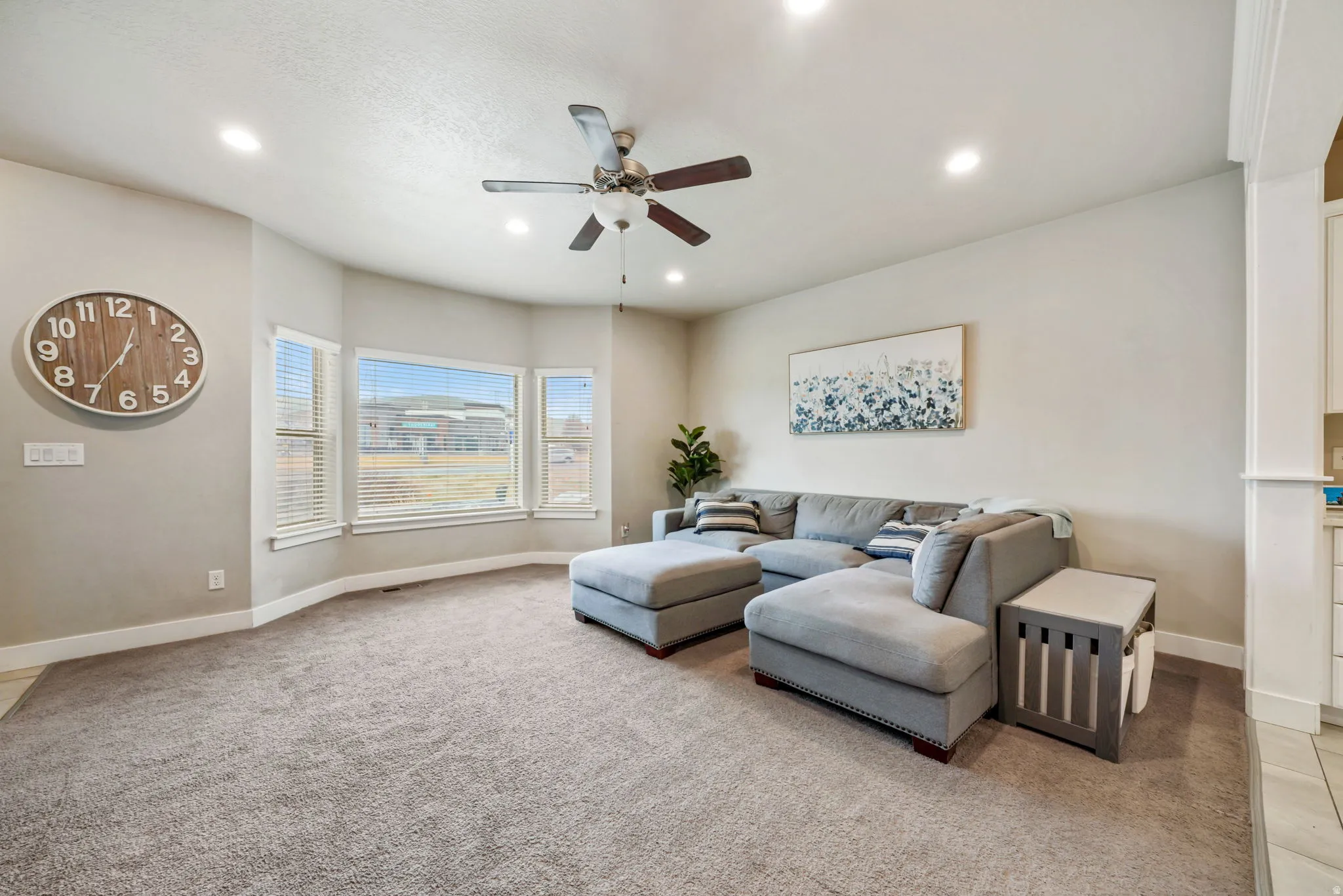 Living area featuring a ceiling fan, recessed lighting, and light carpet