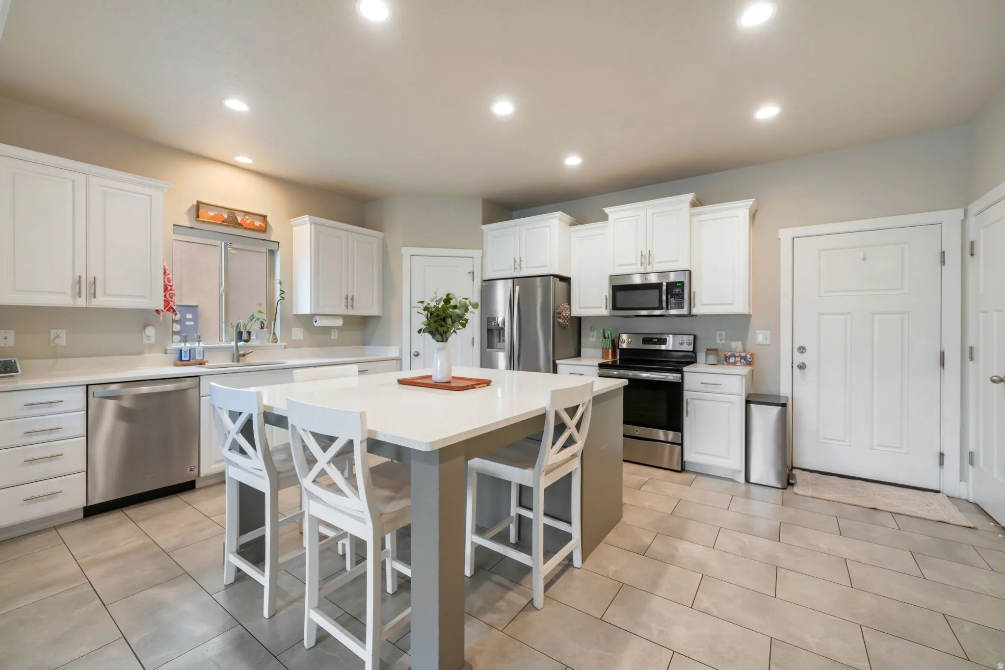 Kitchen with stainless steel appliances, white cabinetry, a kitchen bar, a center island, and recessed lighting
