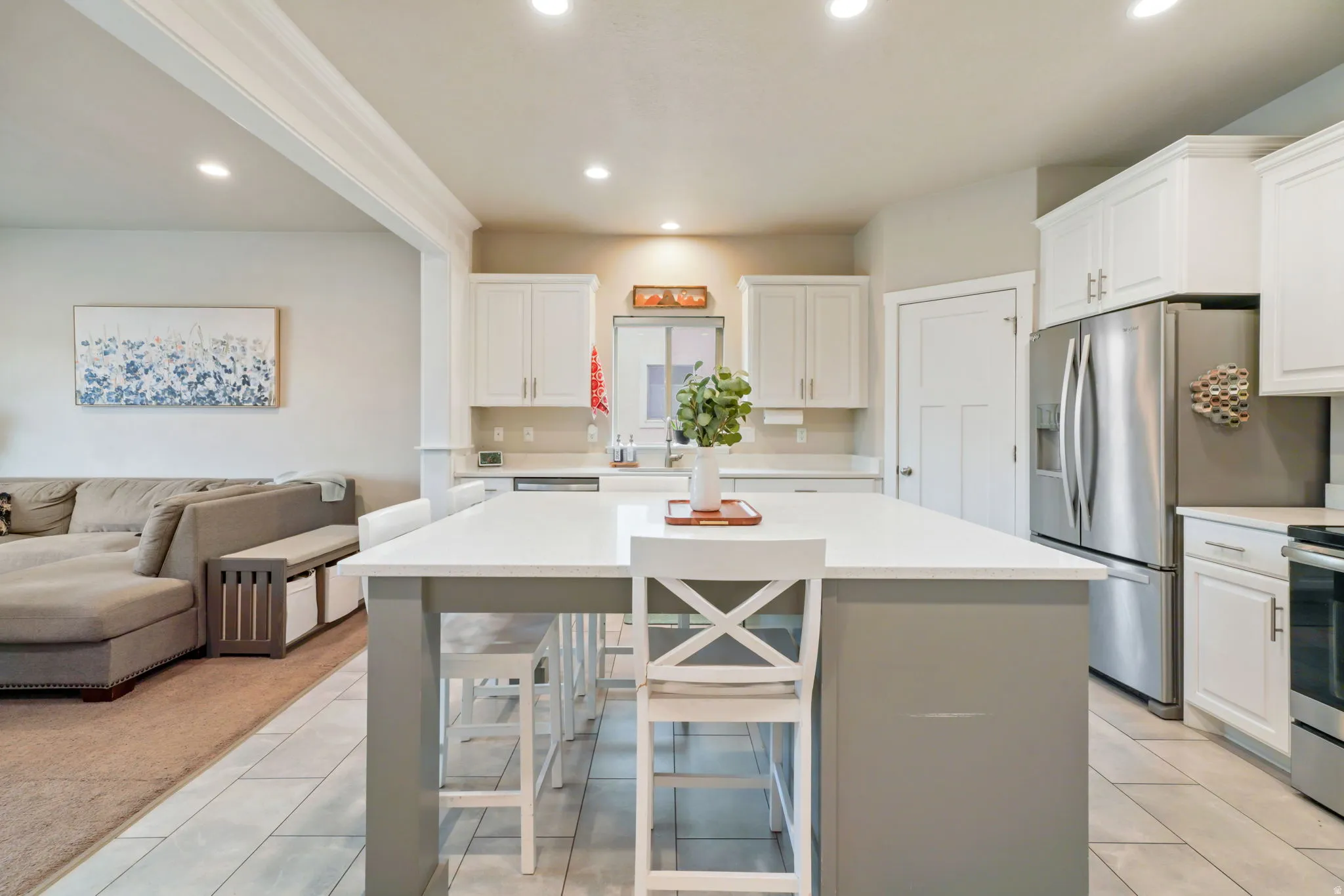 Two tone kitchen featuring open floor plan, a breakfast bar area, a kitchen island, stainless steel appliances, and recessed lighting