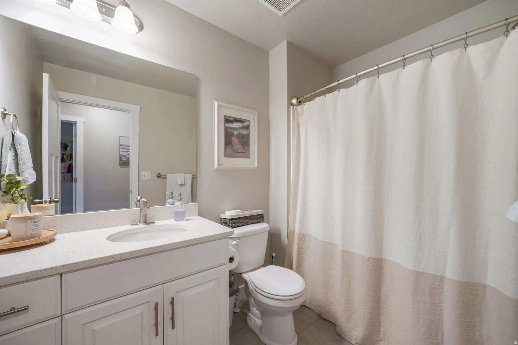 Full bath with curtained shower, vanity, and dark tile patterned flooring