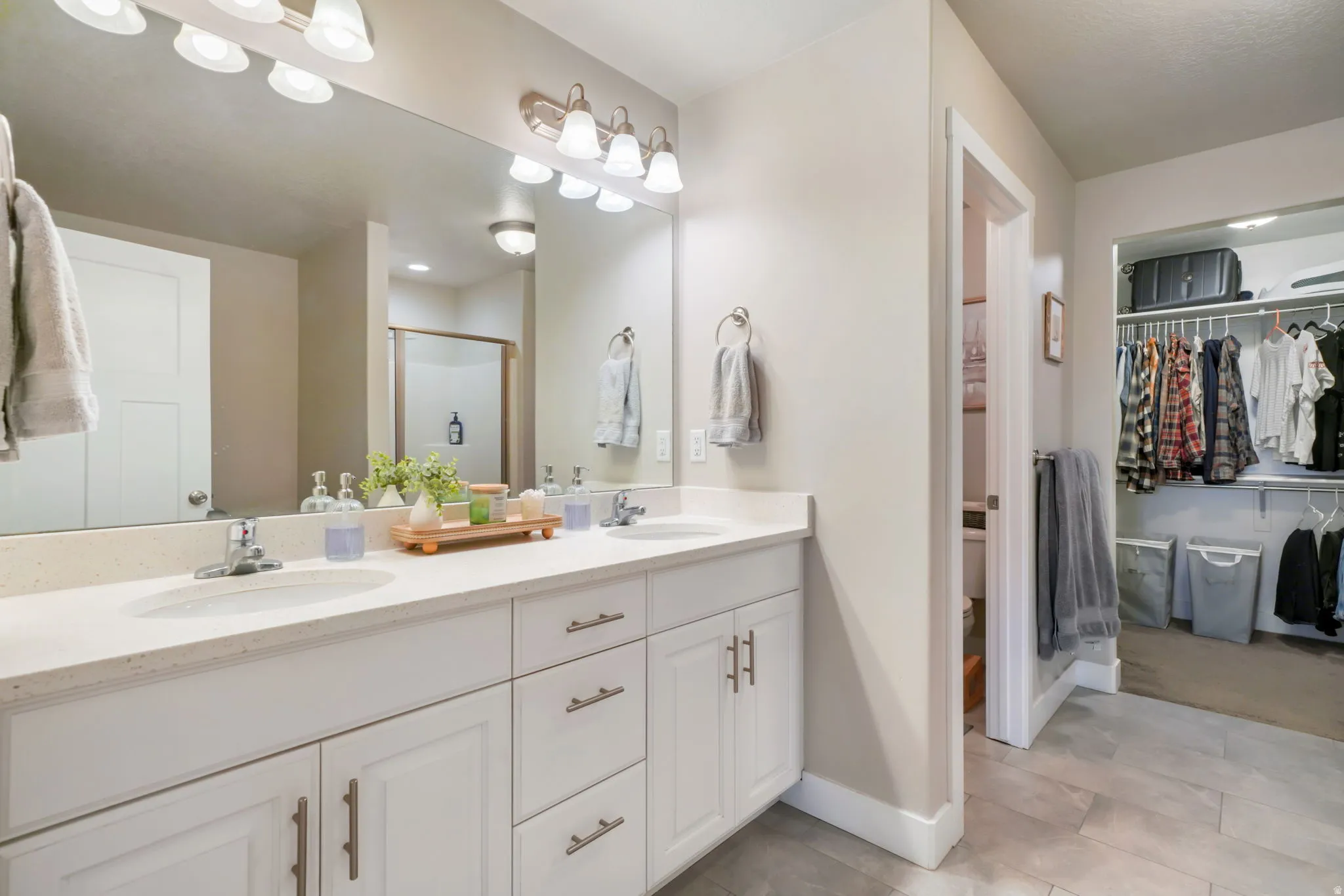 Bathroom featuring double vanity, a shower stall, and a spacious closet