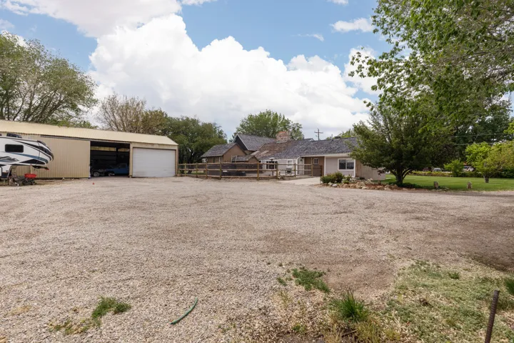 View of yard with an outdoor structure, a garage, driveway, and a carport