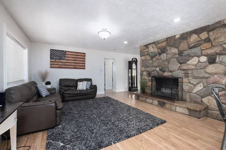 Living room featuring a stone fireplace, light wood-style floors, and a textured ceiling